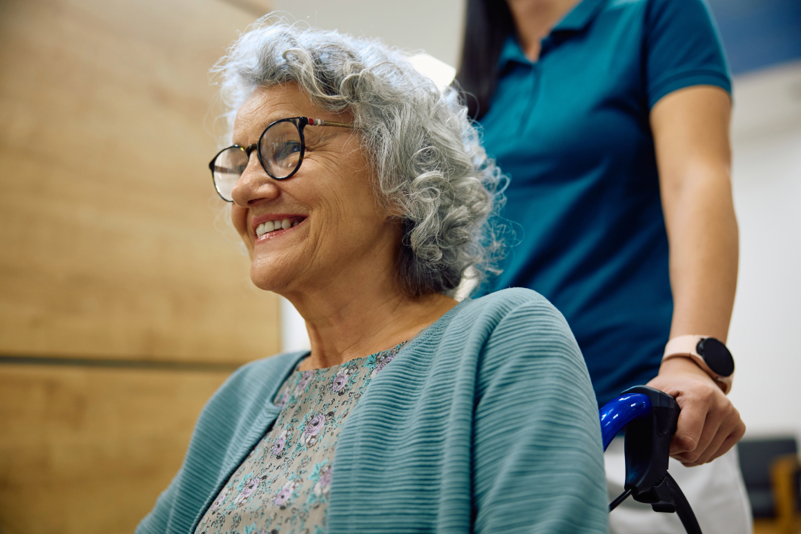 An elderly woman in an assisted living facility getting assistance from a caregiver.